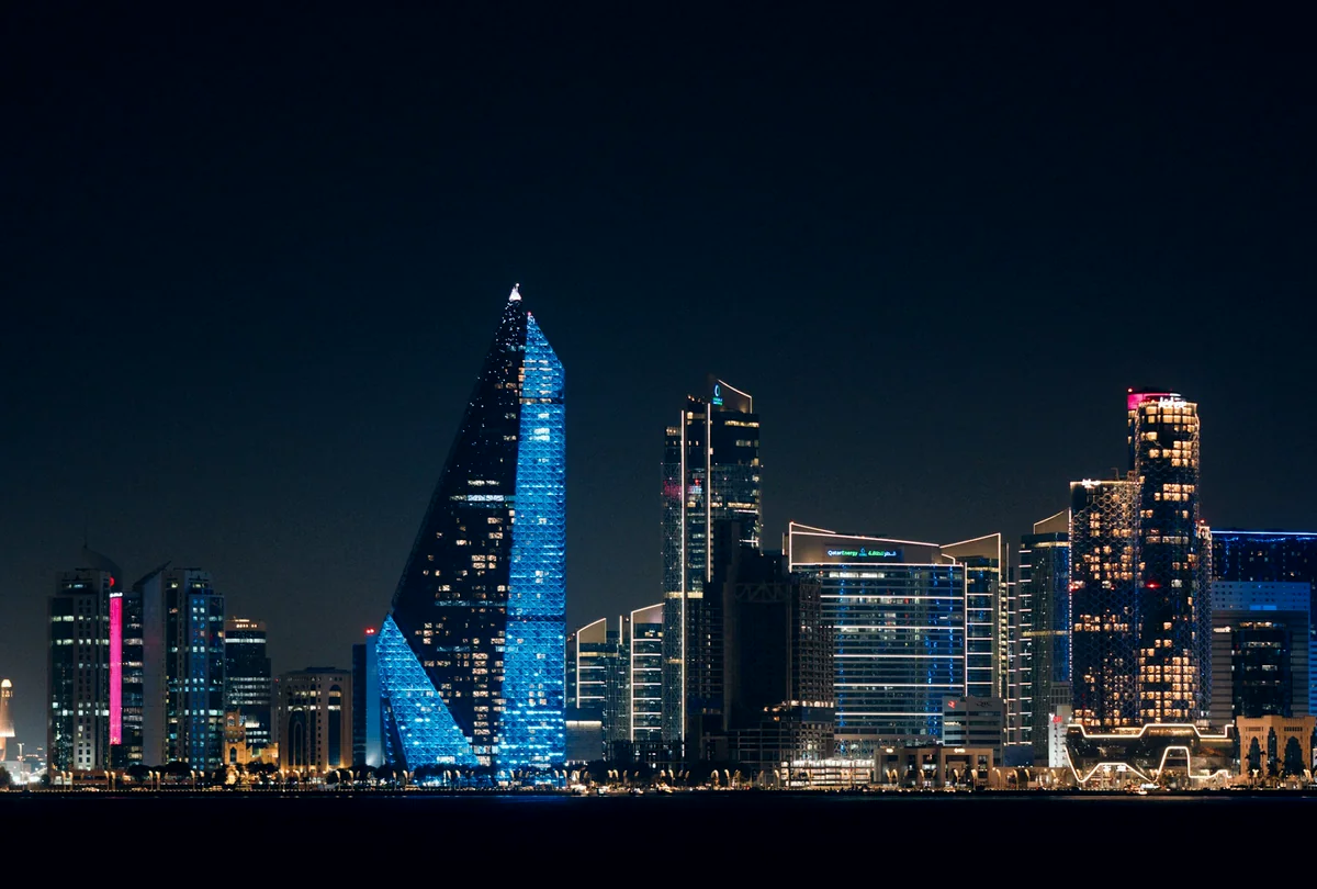 The West Bay skyline in Doha at night, its towers lit against the water.